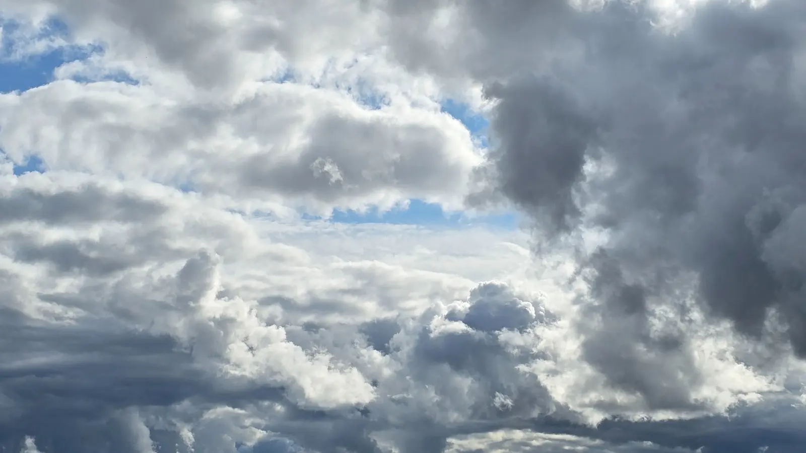 White and dark cumulus clouds in a blue sky